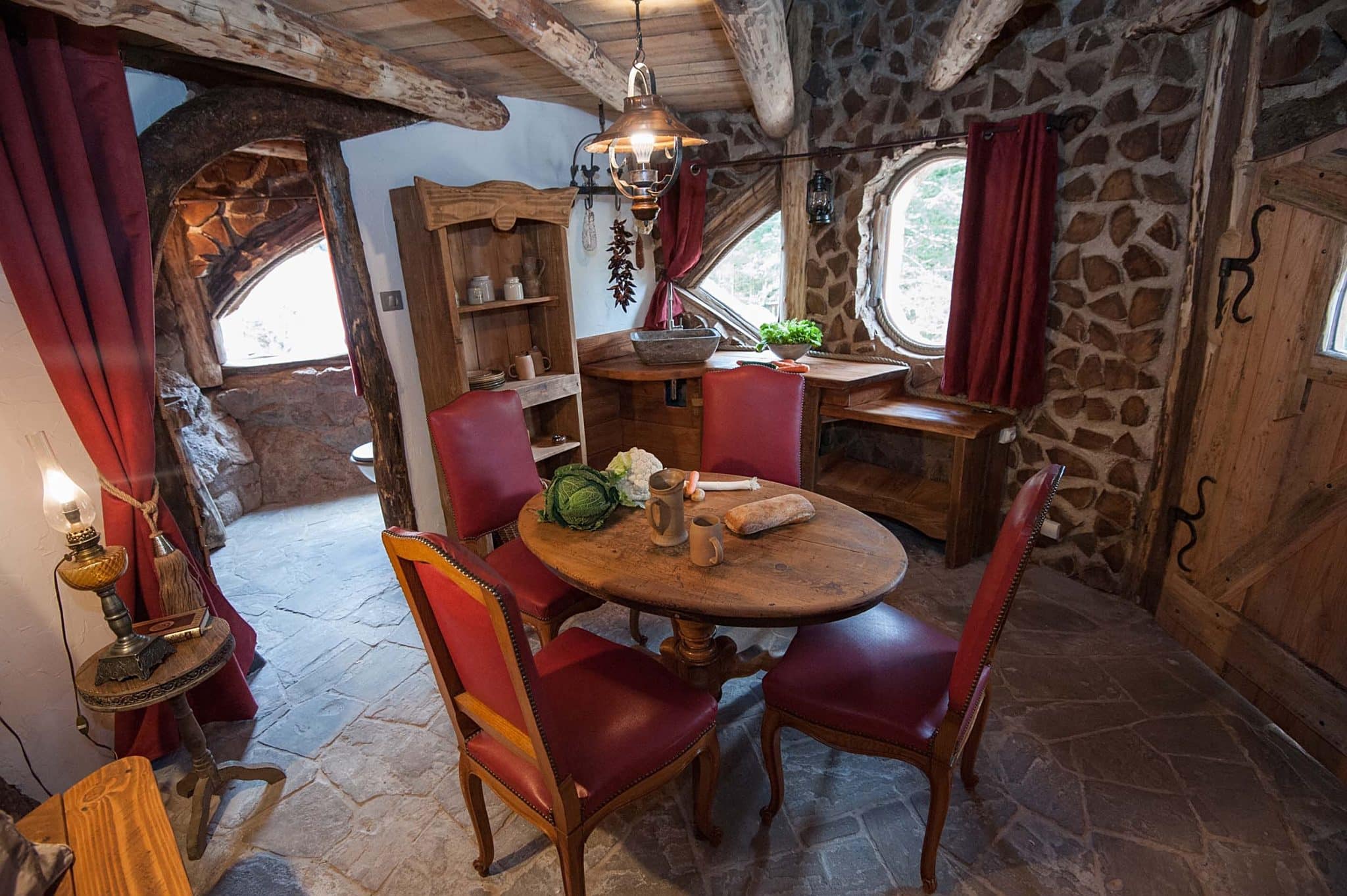 intérieur de la maison du hobbit dans le coin repas avec une table ronde et 4 chaises. de la nourriture est sur la table