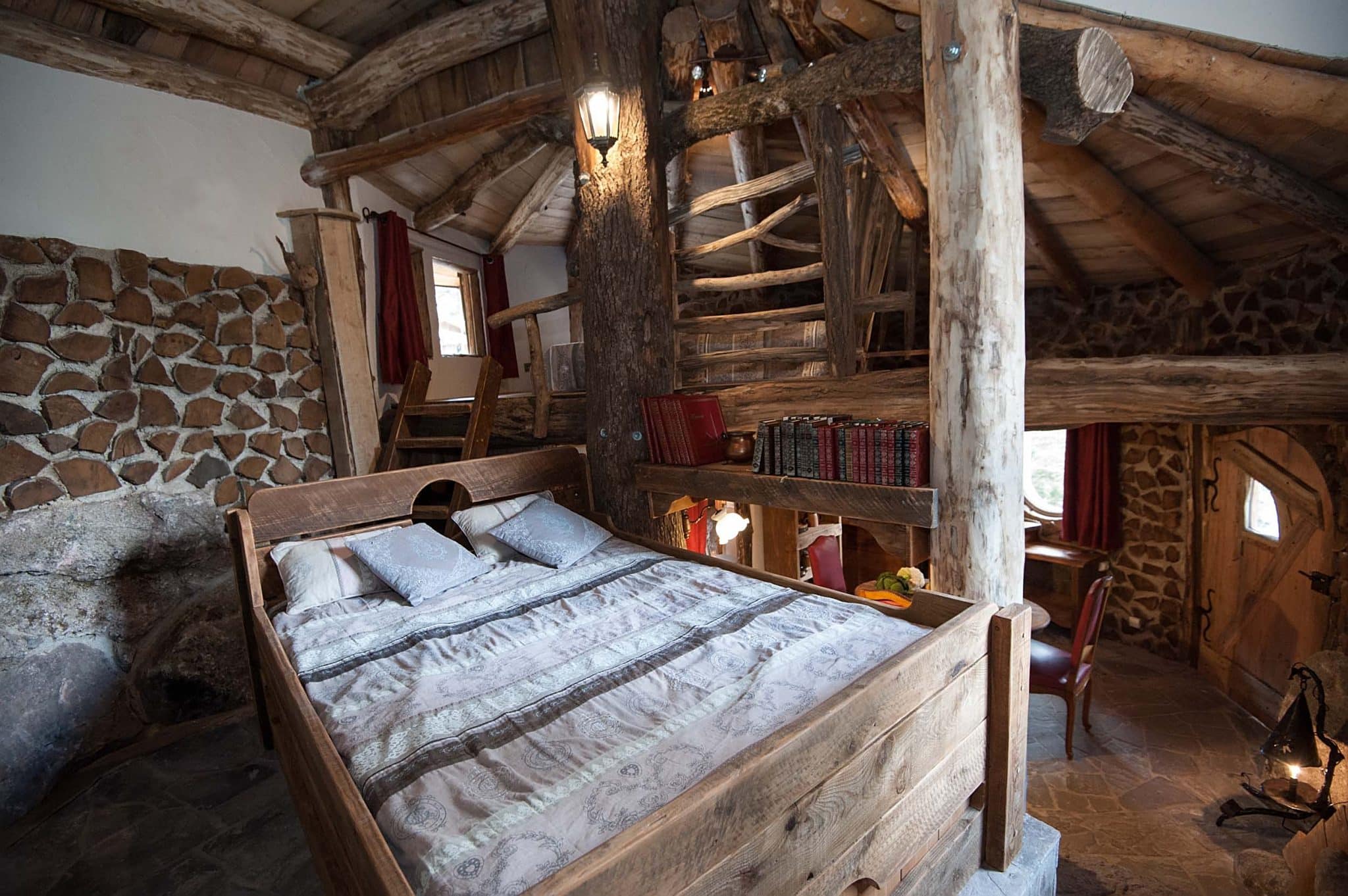intérieur de la maison du hobbit avec la vue sur la chambre avec un lit double , la pièce est ouverte sur le coin repas