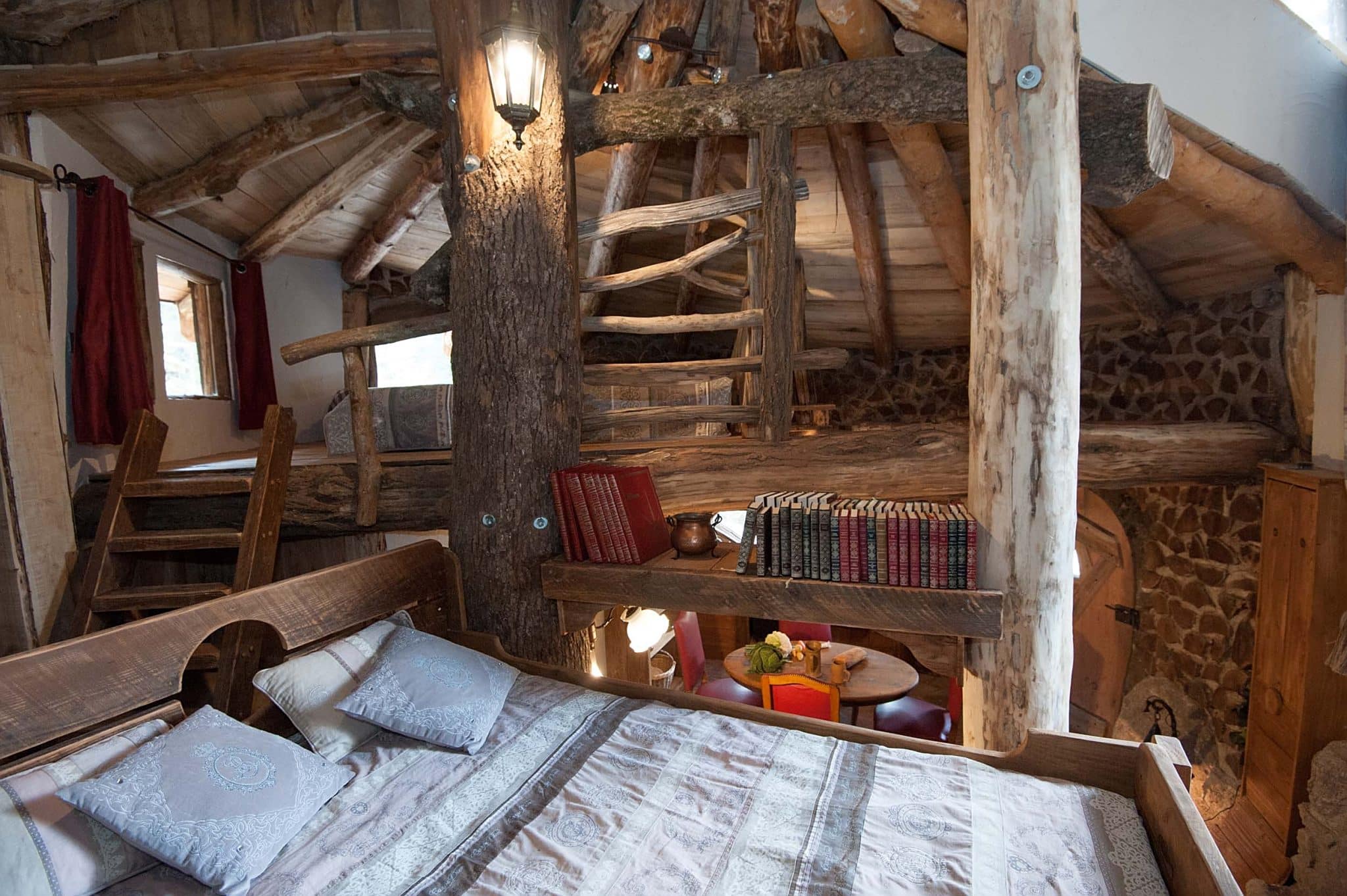 intérieur de la maison du hobbit avec la vue sur la chambre avec un lit double , la pièce est ouverte sur le coin repas