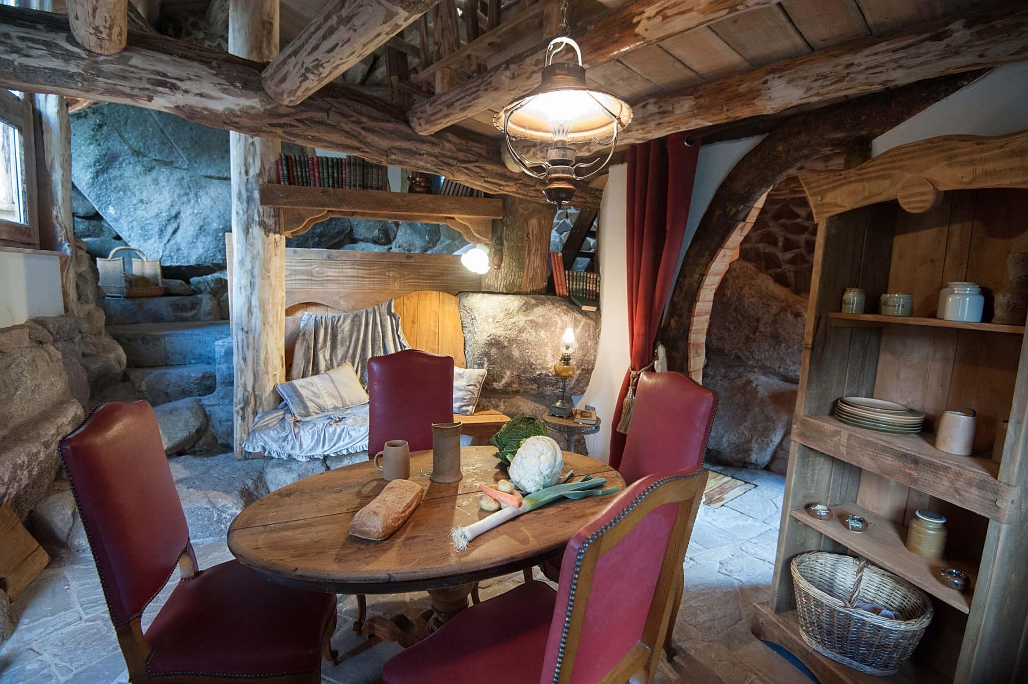 intérieur de la maison du hobbit dans le coin repas avec une table ronde et 4 chaises. de la nourriture est sur la table