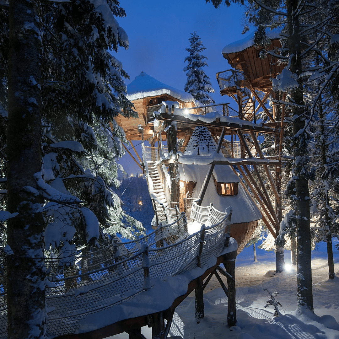 photo de la tribu perchée un hébergement insolite vue de près entre les sapins et de la neige - la lumière est allumée