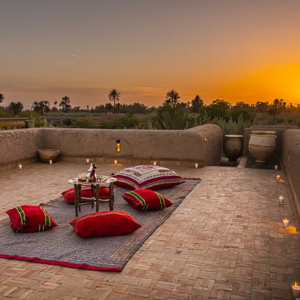 photo de la villa au maroc prise depuis le toit avec l'installation d'un coin thé et l'atlas en fond