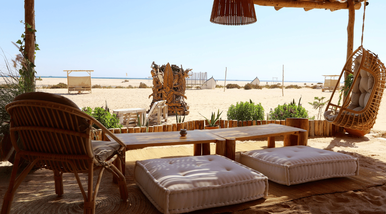 Canapé et chaises sous un porche extérieur avec une vue face a la mer