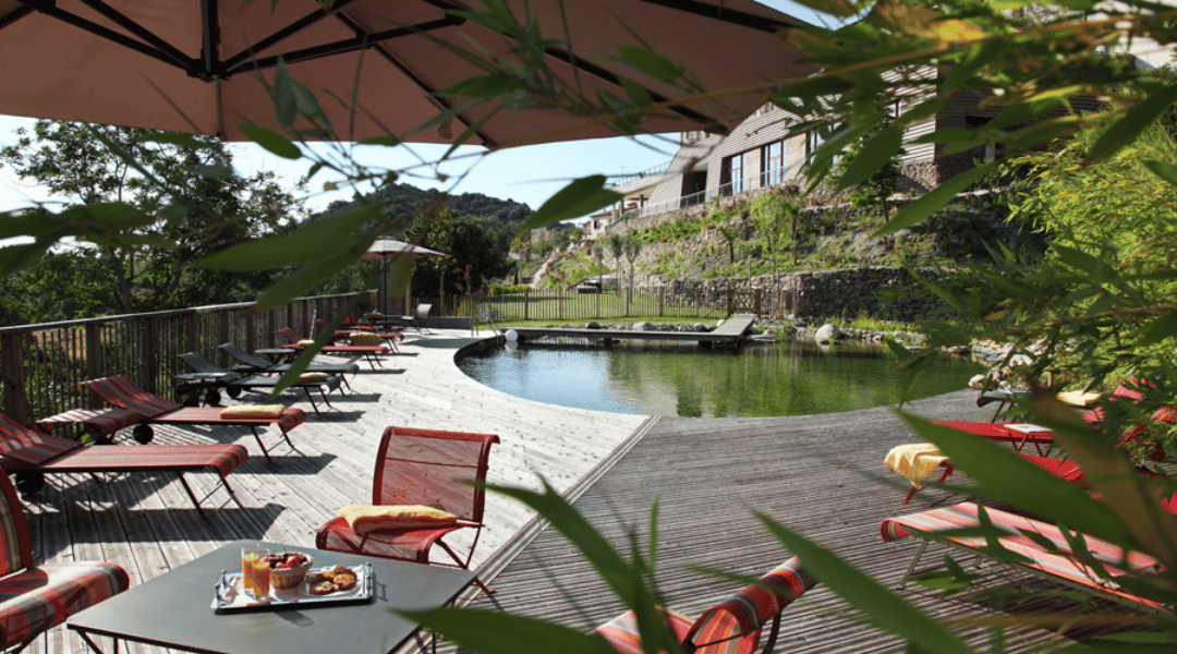 Terrasse avec table et chaise autour d'un bassin naturel